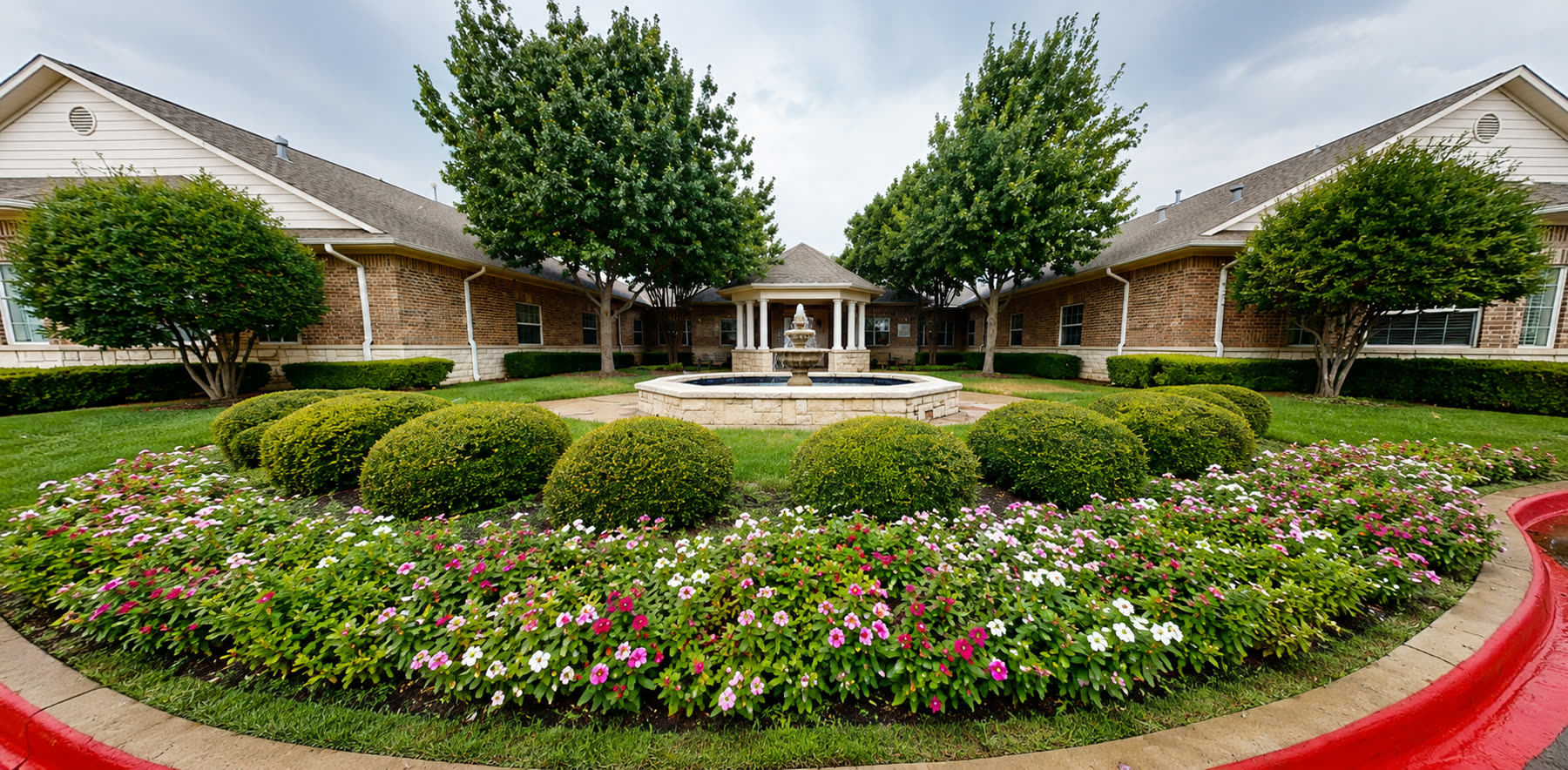 Courtyard fountain surrounded by flower beds and manicured shrubs